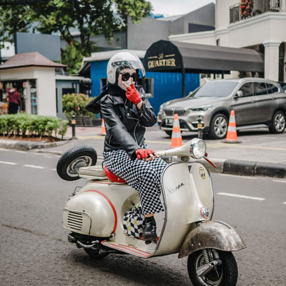 Pengendara vespa wanita sedang memakai sarung tangan Chappo